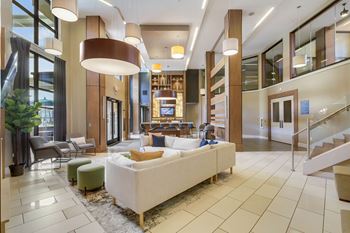 A large white couch is in the middle of a spacious room with a staircase on the right.